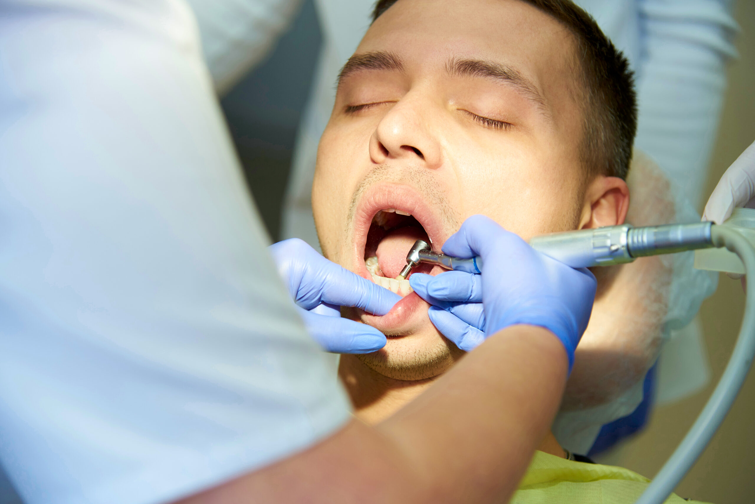 A young man with closed eyes in the dental chair.