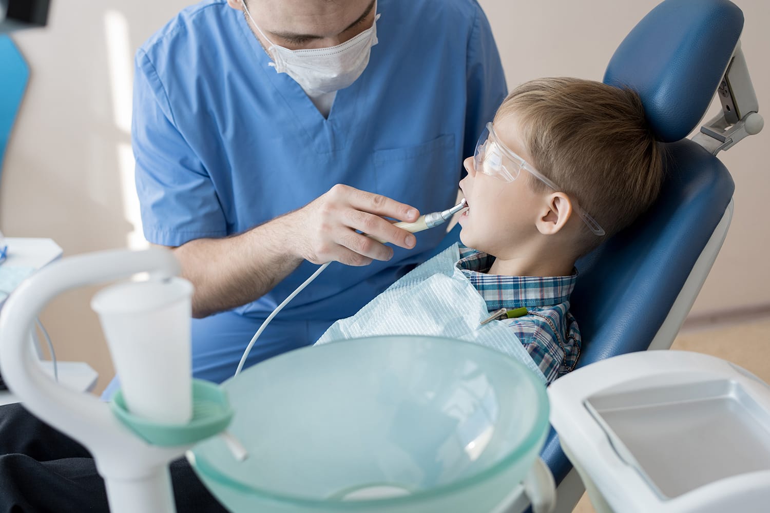 Dentista atendiendo a un niño durante un tratamiento de caries dental