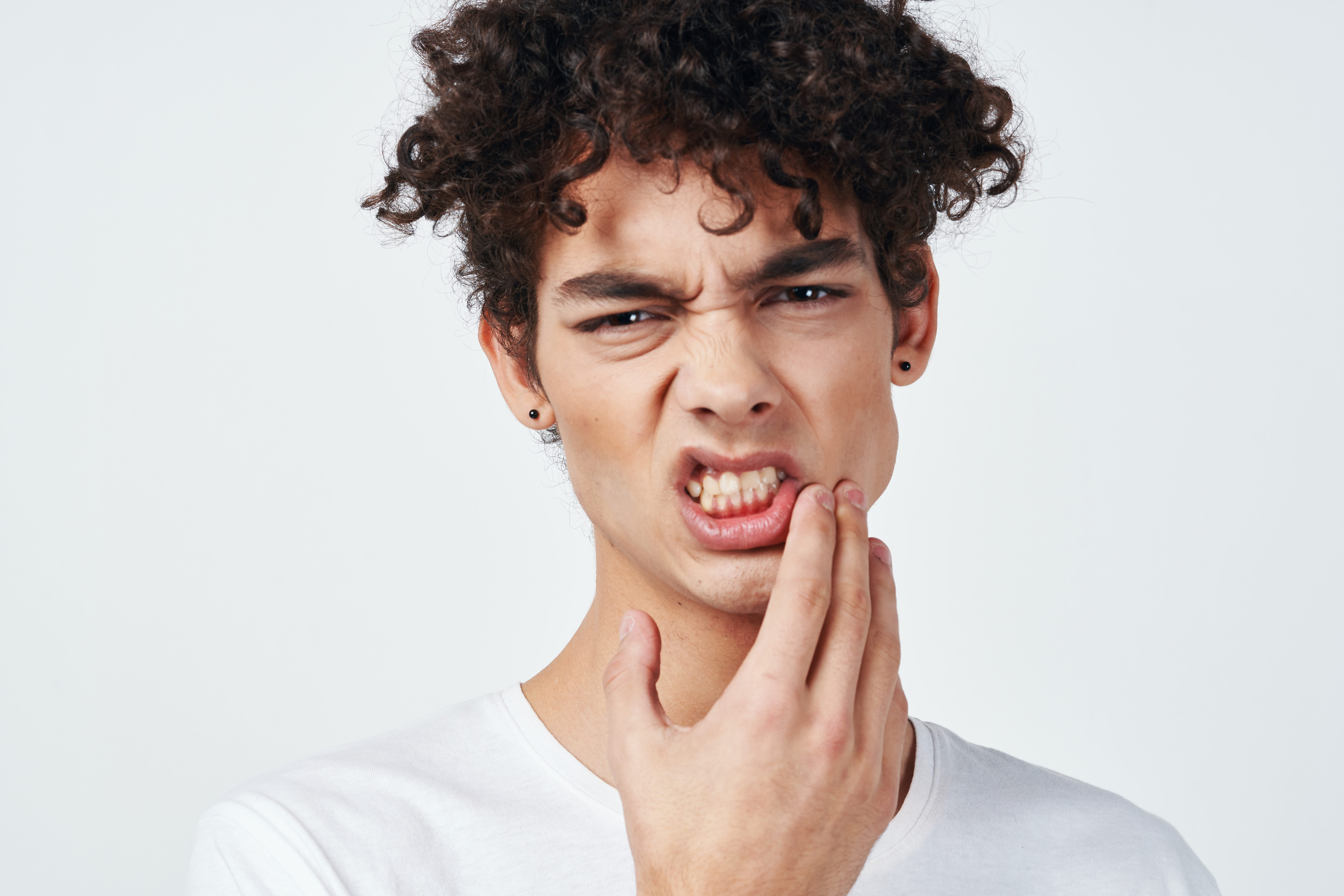 Hombre con dolor dental tocándose la mejilla