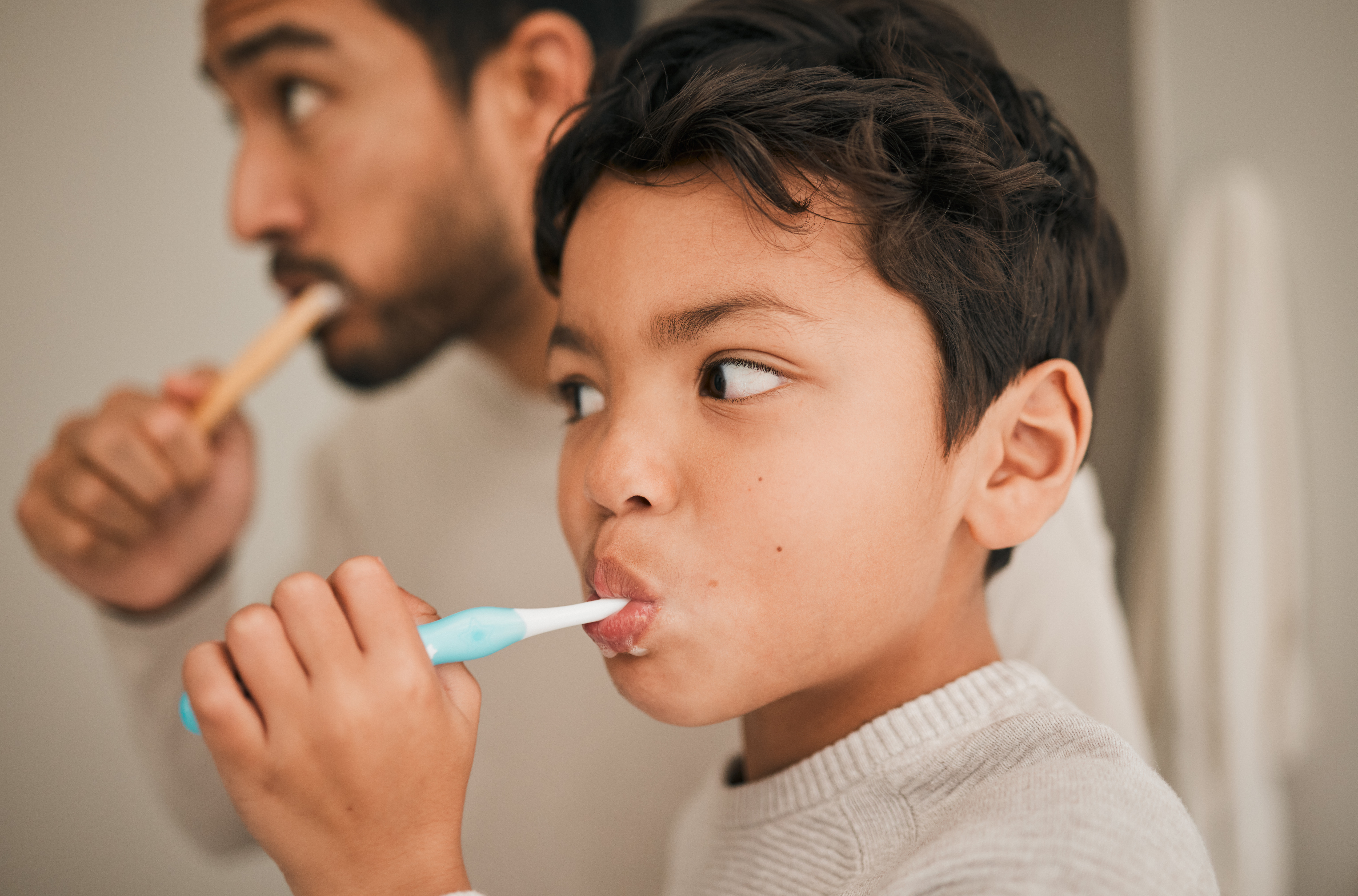 Higiene bucodental infantil en familia Padre ayudando a un niño a cepillarse los dientes